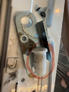 Appliance hinge area showing a misaligned door seal and spacer gap