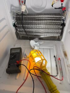 Freezer evaporator coil tested with multimeter during repair