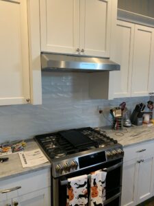 Installed a stainless steel vent hood above a professional-style gas range with a new subway tile backsplash