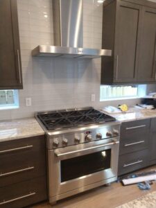 nstalled a stainless steel professional gas range and chimney-style vent hood with a subway tile backsplash